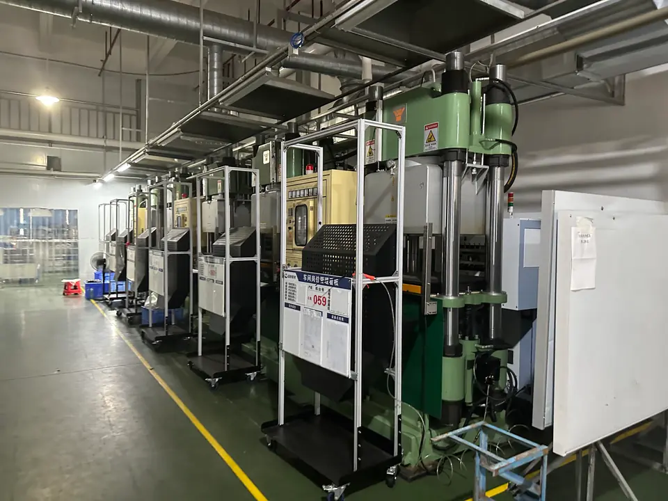 Rows of rubber molding presses arranged beside a marked production aisle